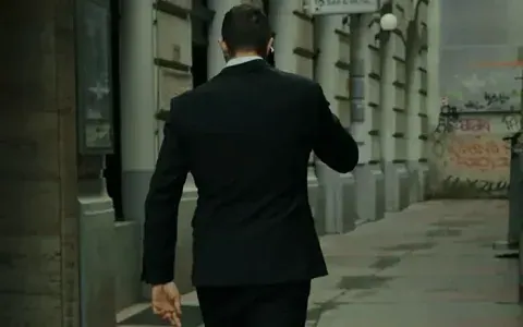 Agent in a dark suit walking down a Viennese alley